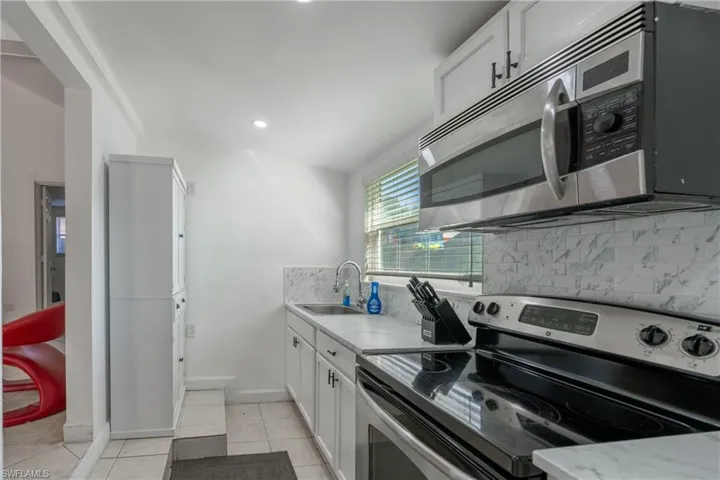 Kitchen with stainless steel appliances, white cabinets, tasteful backsplash, light tile patterned floors, and recessed lighting