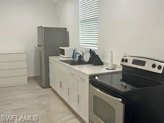 Kitchen with a breakfast bar area, appliances with stainless steel finishes, tasteful backsplash, open floor plan, and white cabinetry