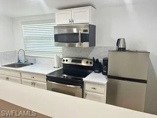 Kitchen featuring white cabinets, stainless steel appliances, and light countertops