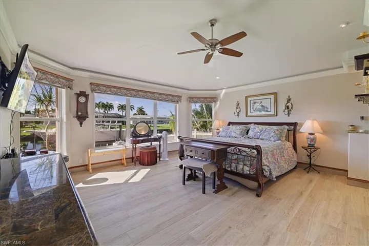 Bedroom with crown molding, light wood-style floors,  ceiling fan and wall of windows