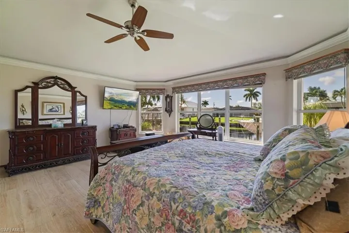 Bedroom featuring crown molding, light wood-style floors, and a ceiling fan