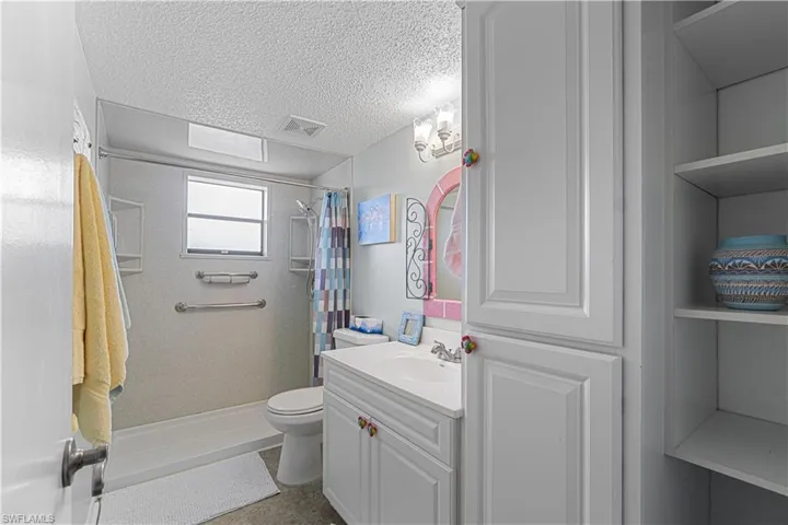 Bathroom featuring a shower with shower curtain, vanity, toilet, and a textured ceiling