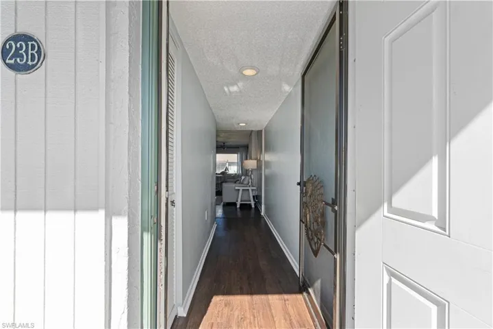 Hallway with a textured ceiling and dark wood-type flooring