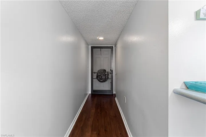 Hallway with dark hardwood / wood-style flooring and a textured ceiling