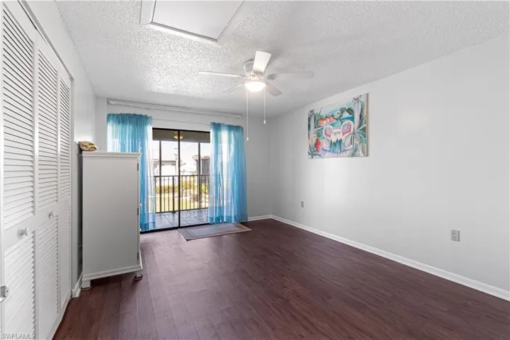 Empty room with a textured ceiling, ceiling fan, and dark wood-type flooring