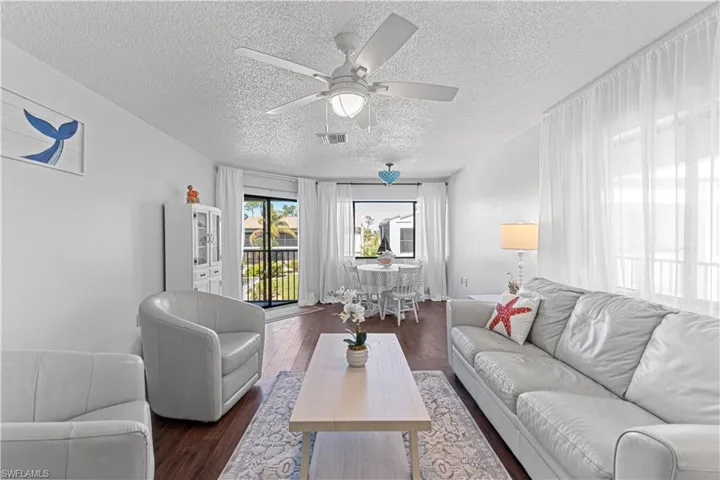 Living room with a textured ceiling, dark hardwood / wood-style floors, and ceiling fan