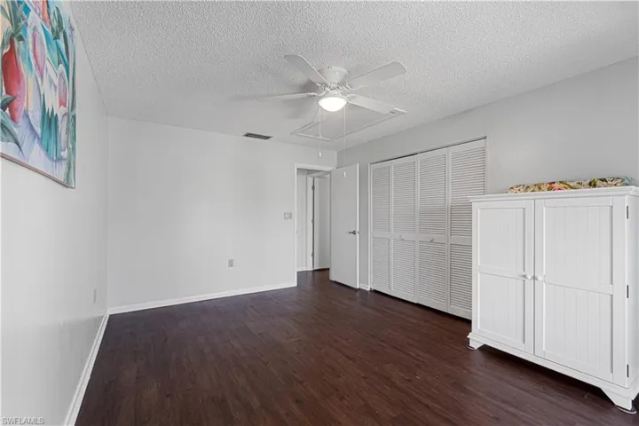 Unfurnished bedroom featuring a closet, a textured ceiling, dark hardwood / wood-style floors, and ceiling fan