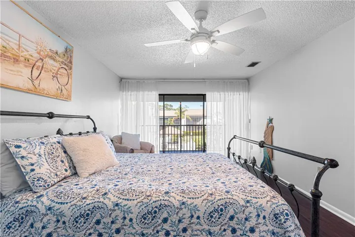 Bedroom with hardwood / wood-style floors, a textured ceiling, access to outside, and ceiling fan