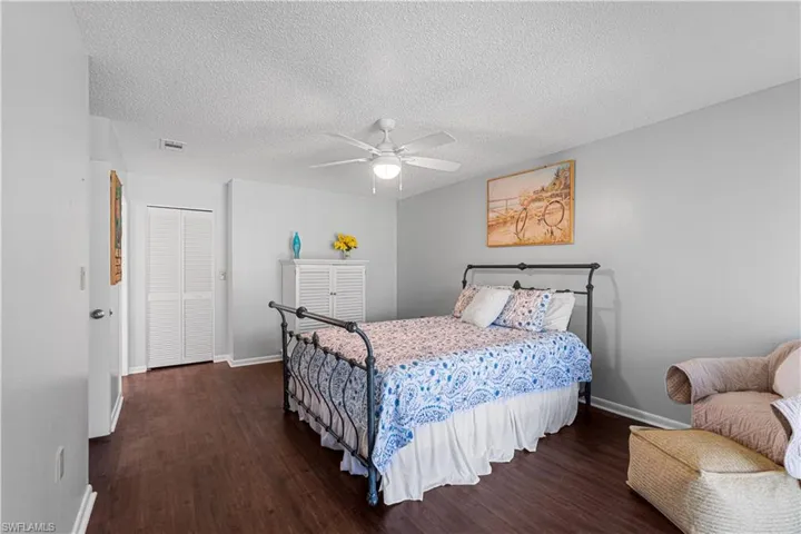 Bedroom featuring a textured ceiling, a closet, dark hardwood / wood-style floors, and ceiling fan