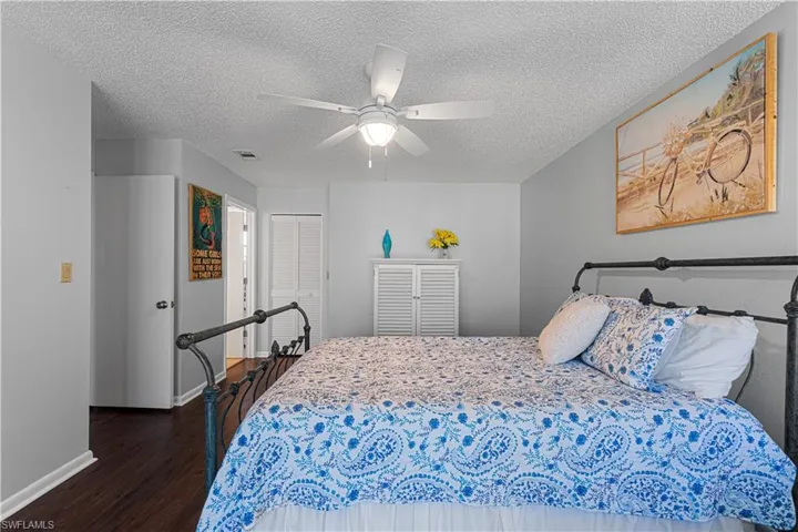 Bedroom with a textured ceiling, dark hardwood / wood-style flooring, a closet, and ceiling fan
