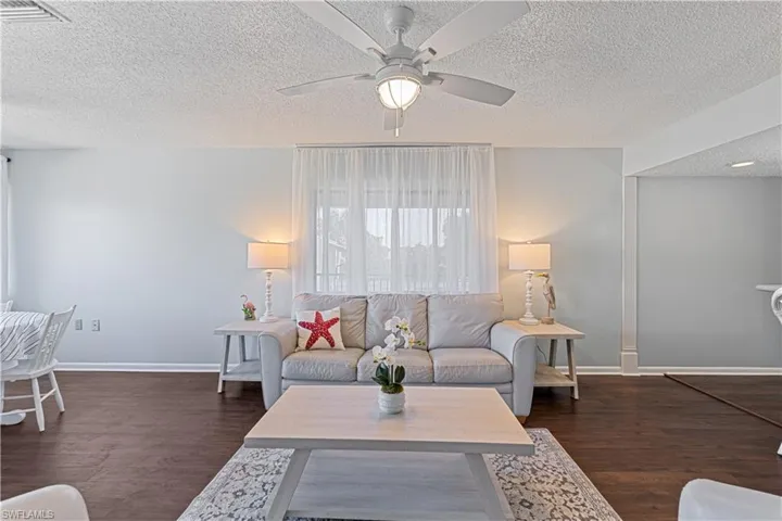 Living room with dark hardwood / wood-style flooring, a textured ceiling, and ceiling fan