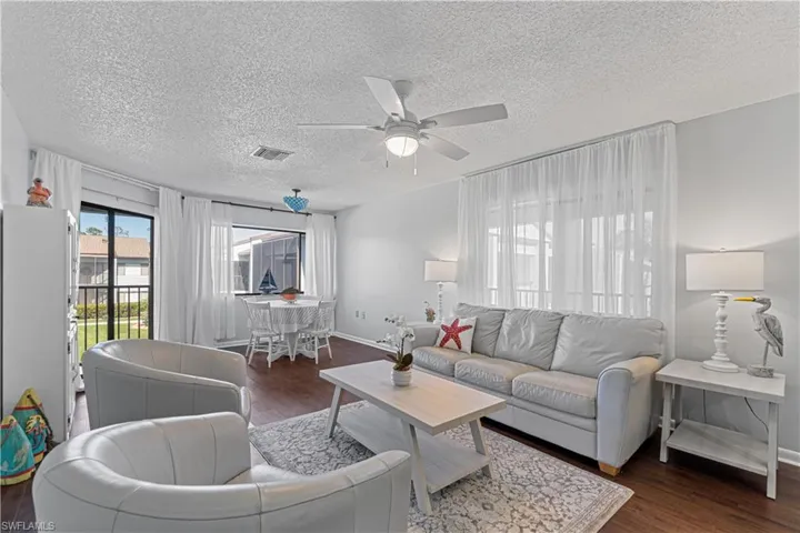 Living room with dark hardwood / wood-style floors, ceiling fan, and a textured ceiling