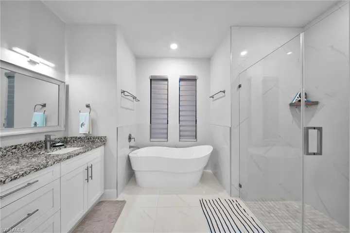 Bathroom featuring vanity and separate shower and tub