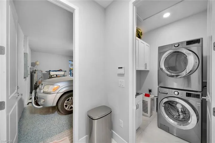 Laundry room with cabinets, stacked washer / dryer, and light tile patterned floors