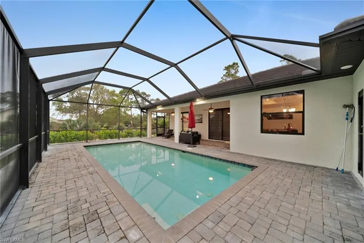 View of swimming pool with an outdoor hangout area, a patio area, and glass enclosure