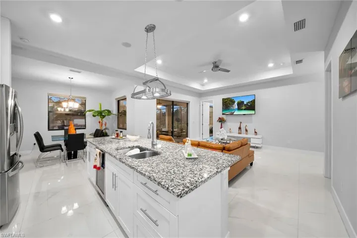 Kitchen featuring white cabinetry, sink, hanging light fixtures, a tray ceiling, and stainless steel appliances