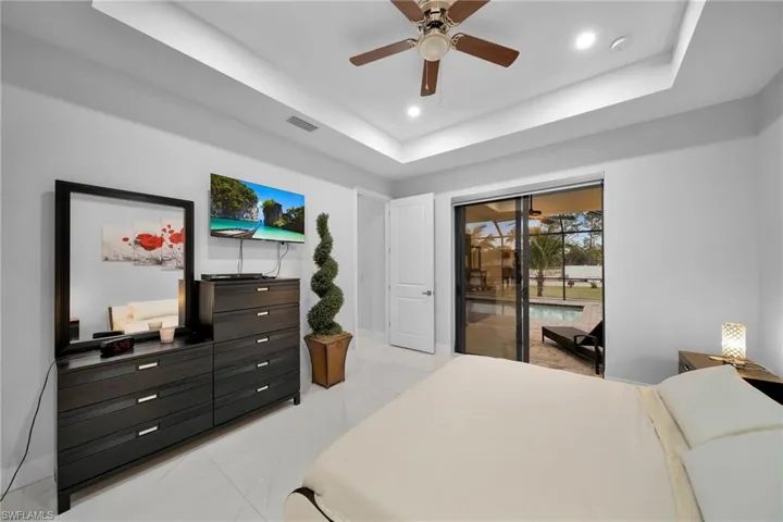 Bedroom with a tray ceiling, access to outside, and ceiling fan