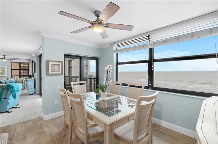 Dining room with ceiling fan, light wood-style flooring, crown molding, and a water view