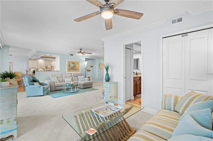 Living room with crown molding, light colored carpet, and a ceiling fan