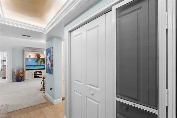 Hallway with crown molding and light wood-style flooring