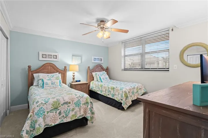 Bedroom featuring crown molding, light carpet, a closet, and a ceiling fan