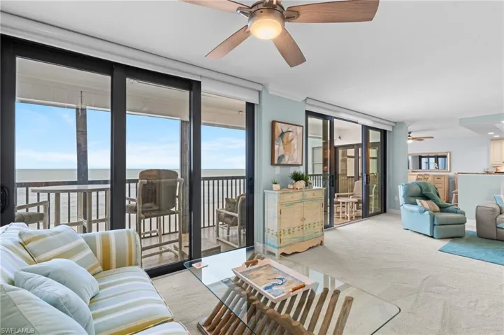 Carpeted living room with a ceiling fan, a water view, floor to ceiling windows, and ornamental molding
