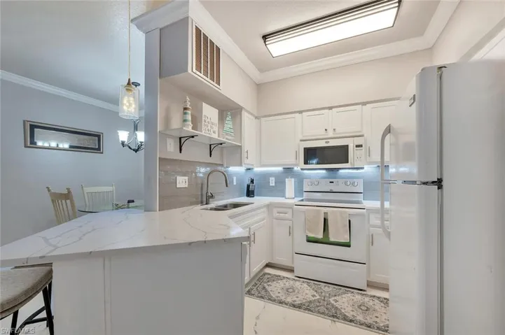 Kitchen featuring open shelves, white appliances, crown molding, white cabinets, and decorative light fixtures