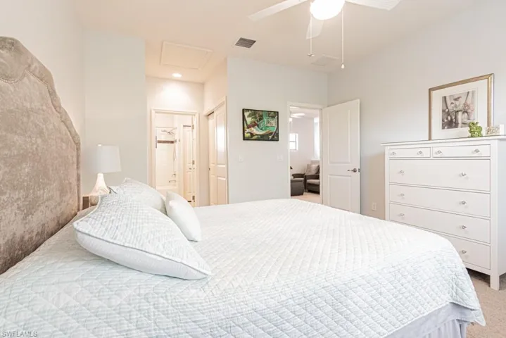 Bedroom featuring light colored carpet, connected bathroom, ceiling fan, and attic access