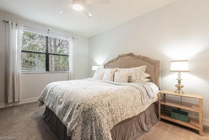 Carpeted bedroom with a ceiling fan and lofted ceiling