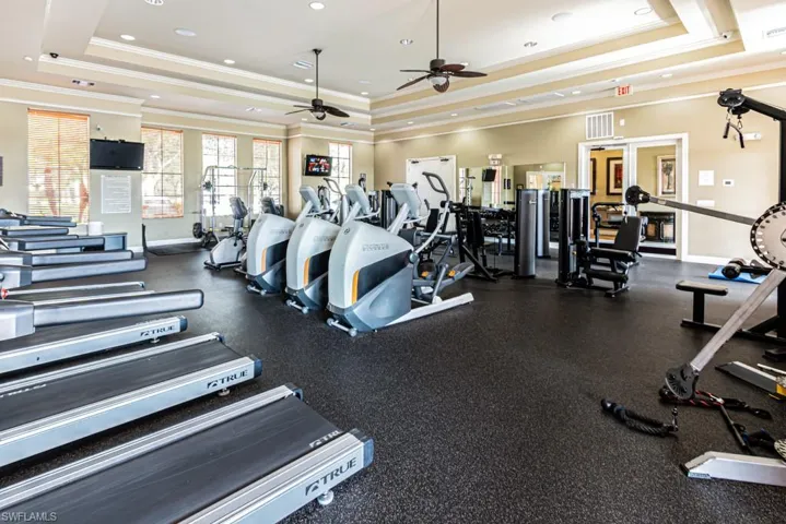 Exercise room with a tray ceiling, ornamental molding, and a ceiling fan