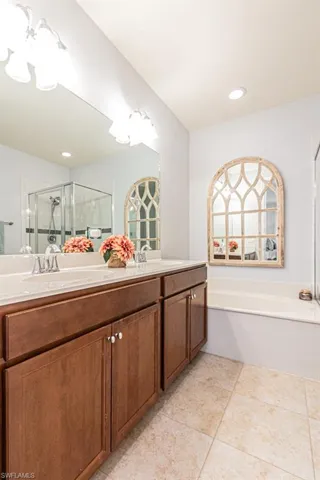 Full bathroom featuring a bath, double vanity, a shower stall, and tile patterned flooring