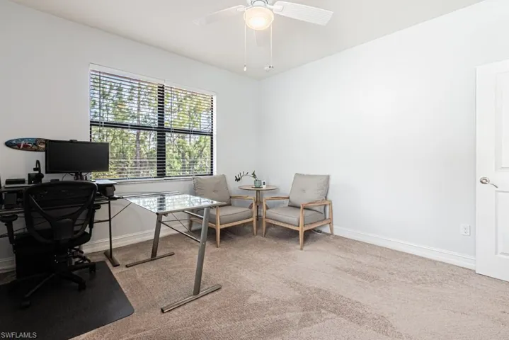 Carpeted office space featuring a ceiling fan and baseboards