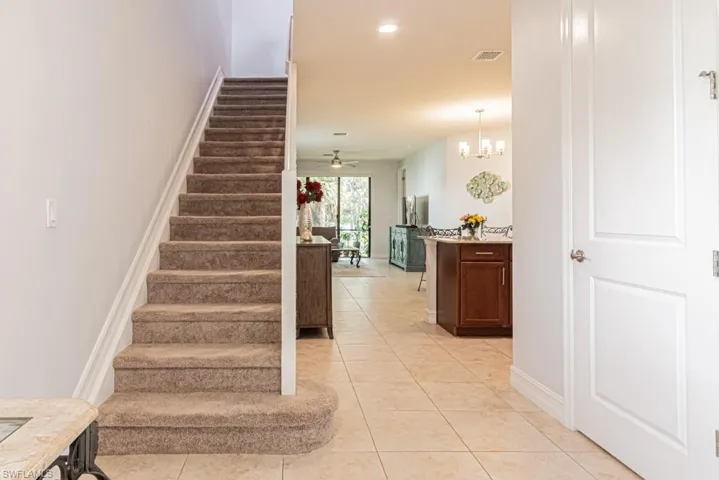 Stairway featuring tile patterned floors, ceiling fan, and a chandelier