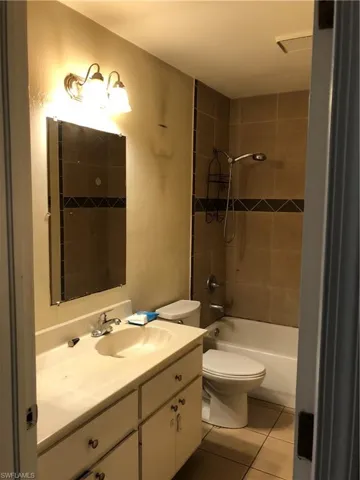Full bath featuring vanity, light tile patterned flooring, and  shower combination