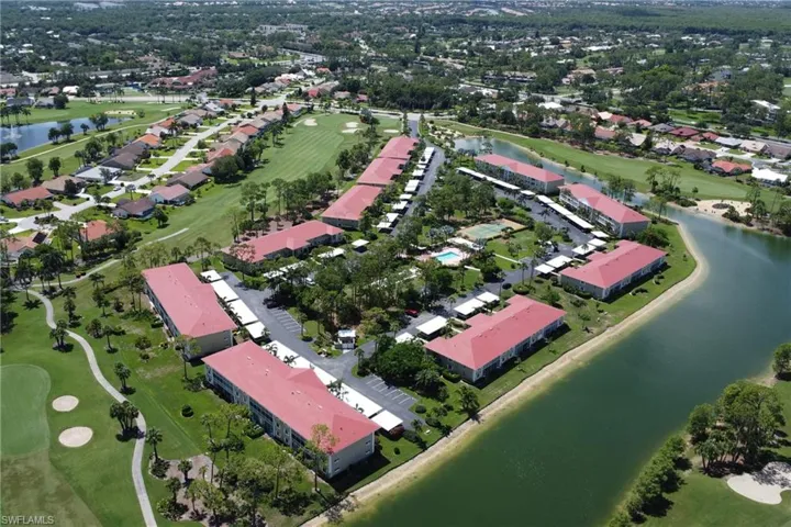 Aerial view of property and surrounding area featuring a golf course and a nearby body of water