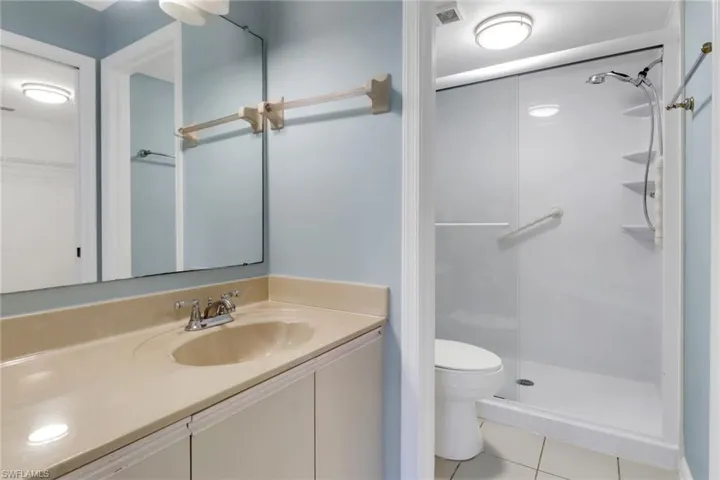 Full bath with vanity, a shower stall, light tile patterned floors, and a walk in closet