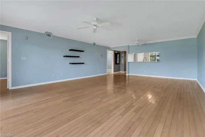 Unfurnished living room with light wood-style flooring, a ceiling fan, crown molding, and a textured ceiling