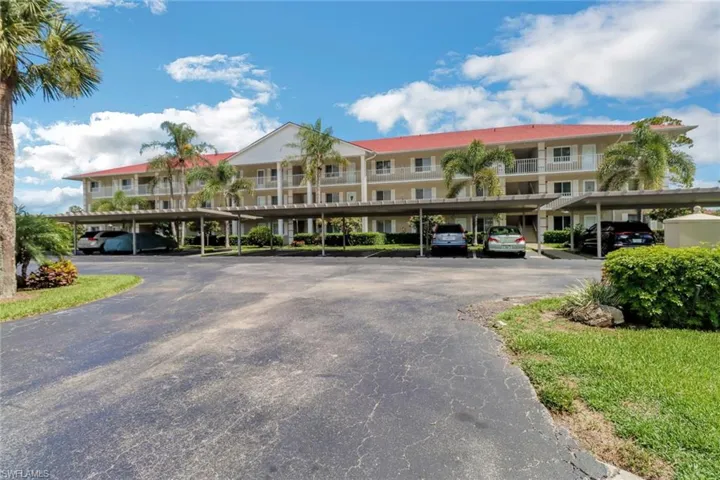 View of apartment building / complex featuring covered parking