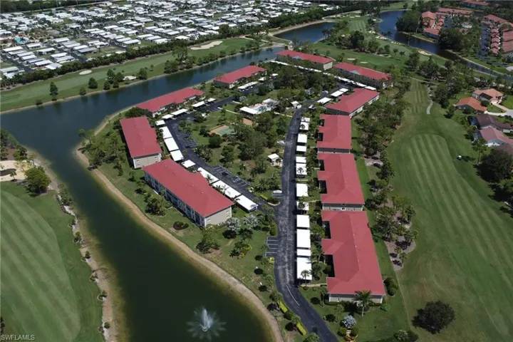 Aerial view of property and surrounding area featuring a large body of water, a golf course, and nearby suburban area
