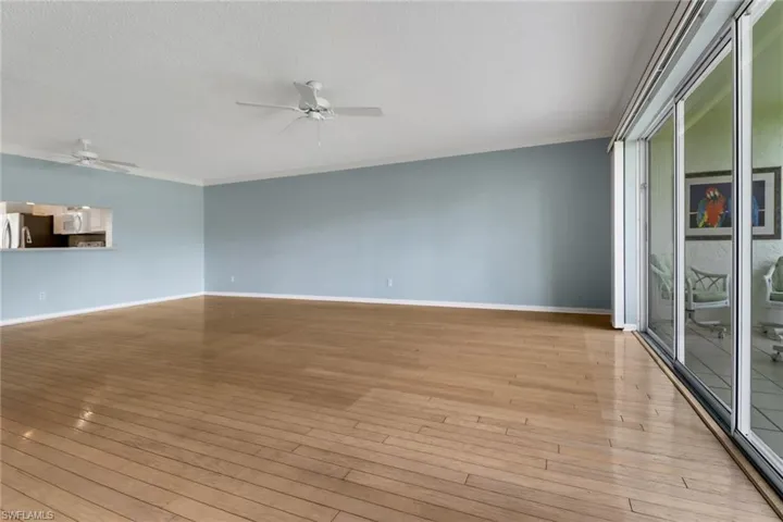 Unfurnished living room featuring a ceiling fan, light wood-style flooring, a textured ceiling, and ornamental molding