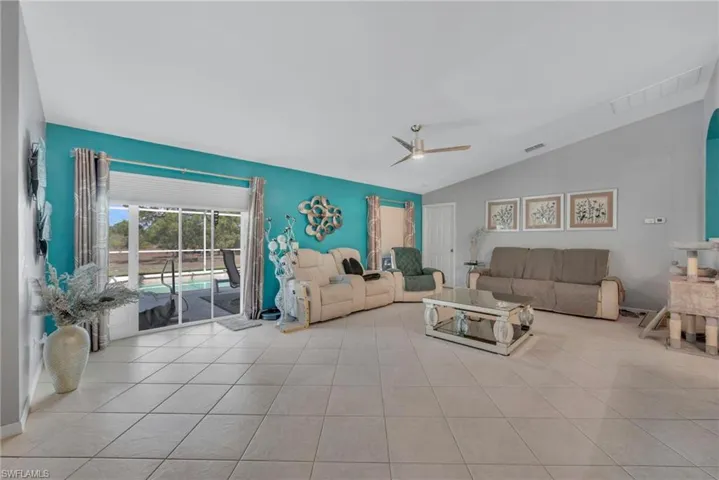 Living area featuring ceiling fan, vaulted ceiling, and light tile patterned floors