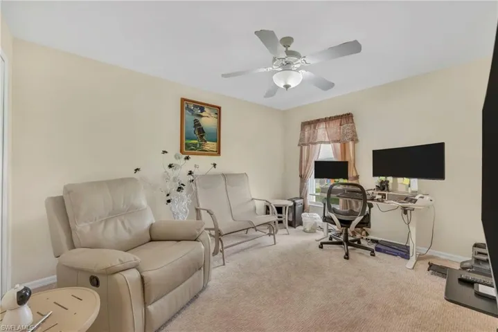 Carpeted office with baseboards and a ceiling fan