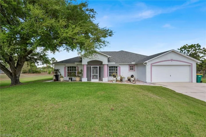 Ranch-style home with a garage, a front yard, stucco siding, driveway, and a shingled roof