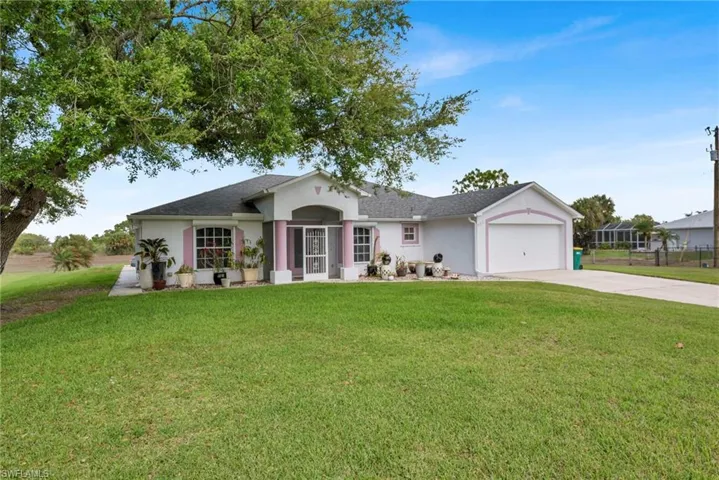 Single story home featuring a front lawn, driveway, a garage, stucco siding, and roof with shingles