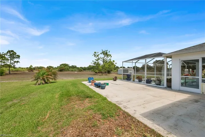 View of green lawn featuring glass enclosure, a patio, and a sunroom