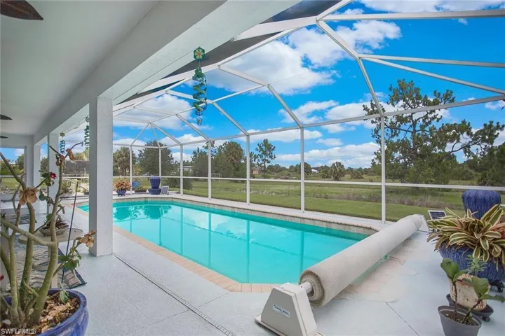 Outdoor pool featuring a sunroom, a patio area, a lawn, and a lanai