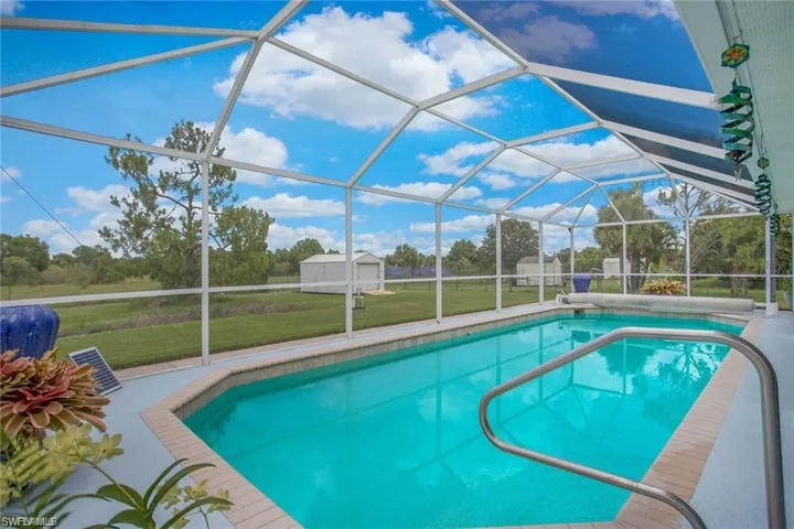 Swimming pool featuring a yard, glass enclosure, and a sunroom