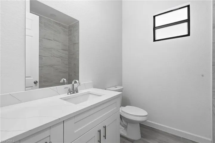 Bathroom featuring a textured wall, vanity, and dark wood-style flooring