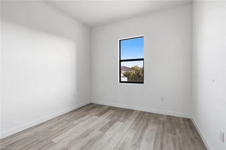 Spare room featuring light wood-type flooring and baseboards