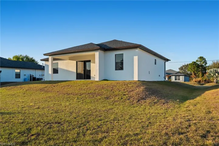 Back of property featuring a lawn, stucco siding, and a patio